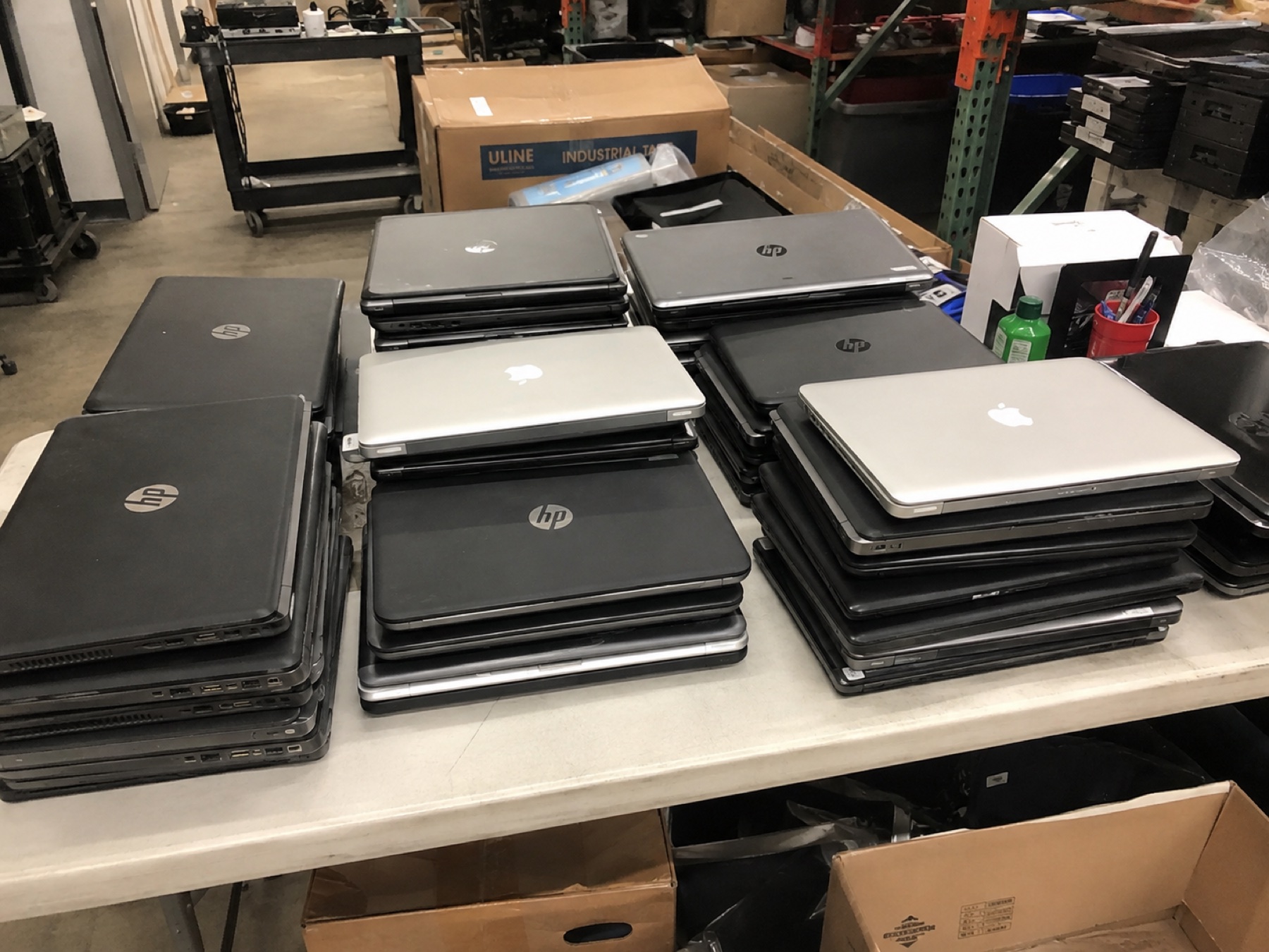 工作枱上分類堆放的 HP 與 Apple 手提電腦